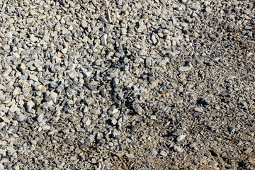 Overhead view of partially compacted crushed stone base with exposed soil at edge for construction groundwork
