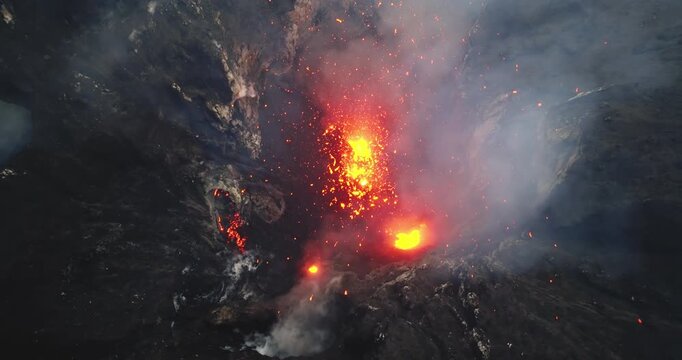 Yasur volcano actively erupting in a dramatic aerial drone view, showcasing hot molten lava exploding from the crater and flowing down the rugged volcanic landscape on Tanna Island in Vanuatu