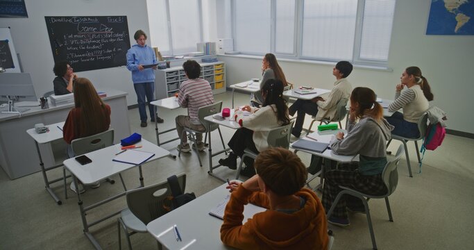 Boy in Blue Hoodie Presents Report on Educational Project For Game Development to Classmates and Teacher. Pupils Listen Intently. Concept Public Speaking Skills, Project Based Learning. Dolly Shot.