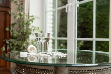 Prevention of colds. Glass of Water and Pills on Table Health and Medication Concept