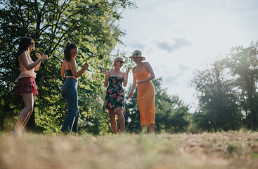A group of friends in casual summer outfits dance and chat in a sunlit park, capturing carefree moments of friendship and outdoor fun.