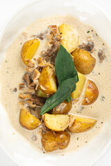 Baked baby potatoes with minced meat and cream sauce served in white bowl on white background