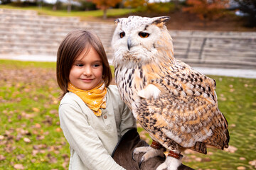 Young caucasian child with eurasian eagle owl in park setting