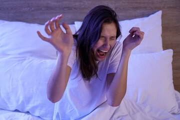 Naklejka premium Scared young woman screaming in bedroom at night