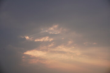 Golden sunset behind soft clouds with warm tones and subtle reflections