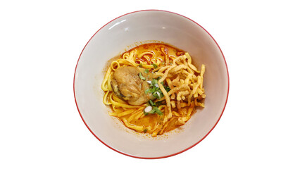 Delicious bowl of Thai Khao Soi with curry broth, egg noodles, chicken drumstick, crispy noodles, and herbs on white background
