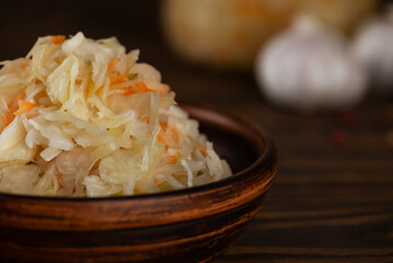 Fresh homemade sauerkraut or fermented cabbage with carrots on a wooden table, closeup.