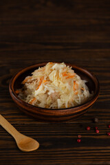 Fresh homemade sauerkraut salad with carrots on a wooden table. Vertical orientation.