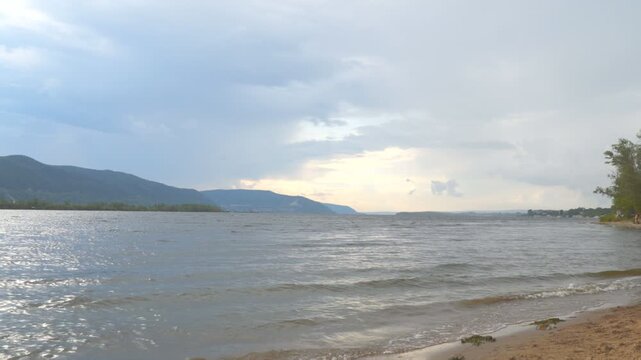View of the Zhiguli mountains from the sandy shore in cloudy weather. The Volga River.