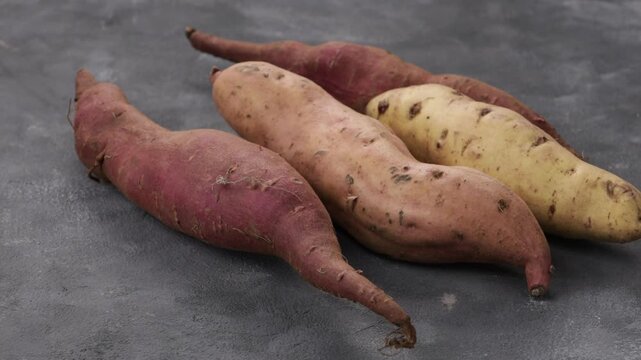 whole sweet potatoes roots close up zoom grey surface