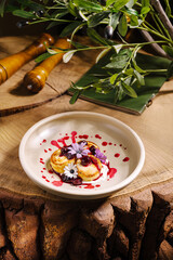 Delicate dessert is placed on a cream-colored dish. Surrounded by vibrant flower petals and berry sauce, it sits on a rustic wooden surface, creating a warm and inviting atmosphere.