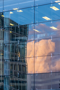 Reflection architecture of a modern glass building showing cloud pattern and smooth structure design in the contemporary urban skyline with metallic facade symmetry under clear daylight