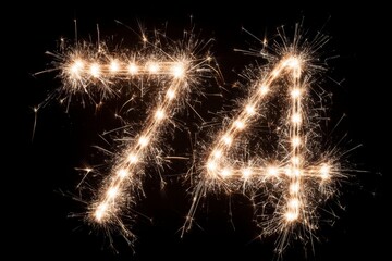 Sparkling Fireworks Create Glowing Number 74 Against Black Background