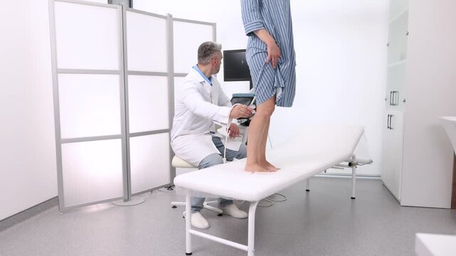 Leg venous ultrasound. Ultrasound vascular diagnostics process of female patient's legs with varicose veins, close-up, side view