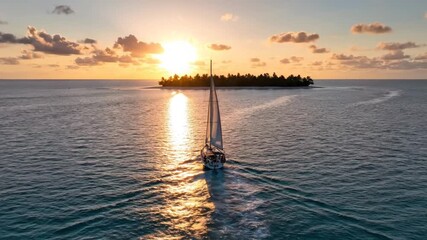 Sailboat glides towards serene island under golden sunset on calm ocean waters
