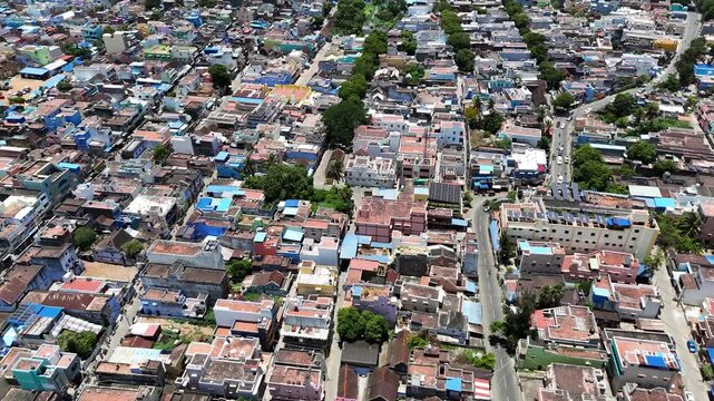 A breathtaking aerial panorama of the Tenkasi district, Tamil Nadu, India, nestled at the base of the Ghats. The scene captures a vibrant townscape with colorful houses surrounded by lush greenery