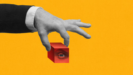 Abstract artwork. Hand holding red cube with hidden eye inside on yellow background. Concept of surveillance, secrecy, corporate observation, and control of hidden information in modern society.