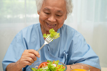 Asian elderly woman patient eating salmon stake and vegetable salad for healthy food in hospital.