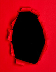 Torn red paper revealing black background in close-up view