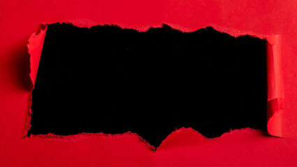 Torn red paper revealing black background in close-up view