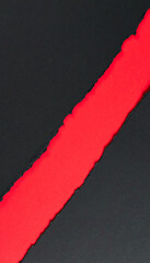 Torn black paper revealing red layer in diagonal composition