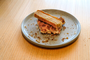 Stack of croffle with cinnamon sugar topping and a slice of garlic bread served on a gray ceramic plate over a wooden table in natural light. Perfect for bakery advertising, cafe menu