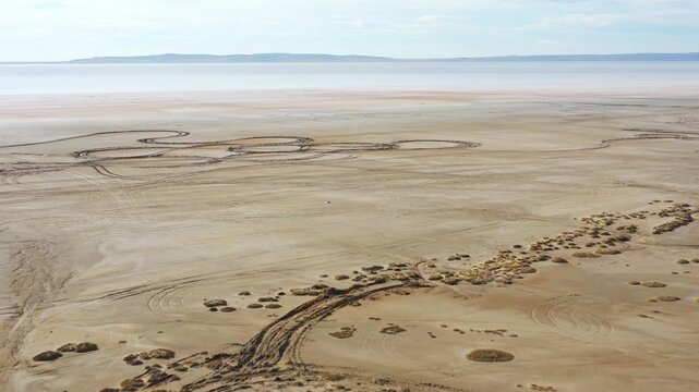 Aerial view of the cracked, arid landscape of Tuz Lake with winding patterns carved into the dry earth, Tuz, Ankara, Turkiye.