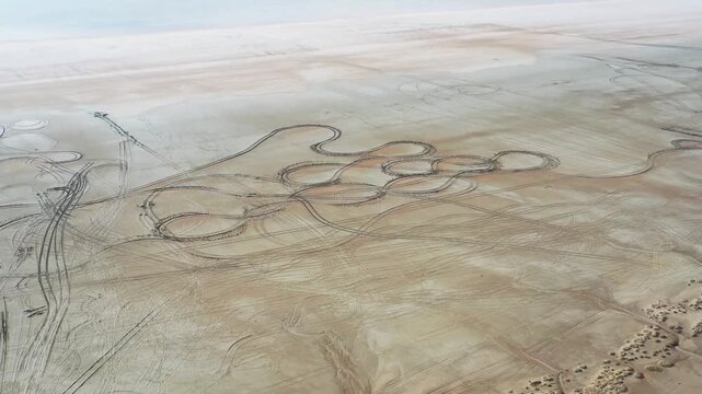 Aerial view of tire tracks creating patterns on the arid land, with a mix of beige and brown hues, Tuz, Ankara, Turkiye.