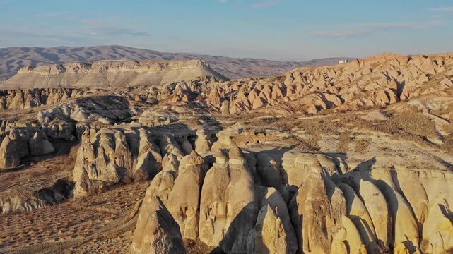 Aerial view of the Cappadocia landscape, revealing the unique geological formations and fairy chimneys in warm earthy tones, Goreme, Cappadocia, Turkiye.