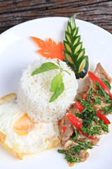 Pad kra pao moo (stir-fried thai basil with pork) and fried egg on old wood scene
