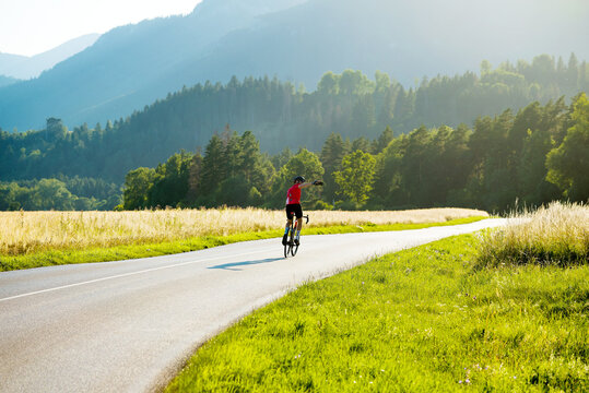 Man in sport gear riding a bicycle down the mountain road while making selfie