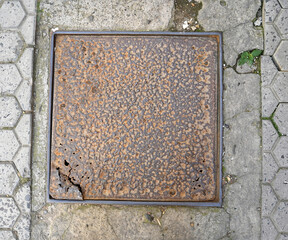 Rusty metal cover on sidewalk reveals age and wear in urban setting