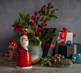 A branch with red berries and a pine branch with cones. Gift packages. Festive mood. Waiting for a Christmas miracle.