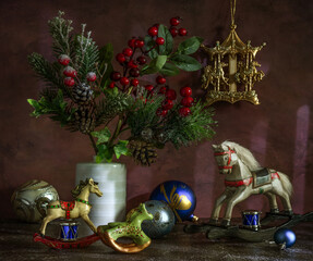 A branch with red berries and a pine branch with cones. Wooden horseshoes and Christmas tree decorations. Festive mood. Waiting for the Christmas miracle.