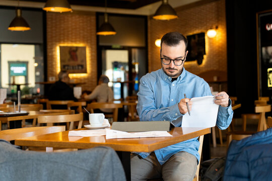 Young man reviewing financial documents in cafe