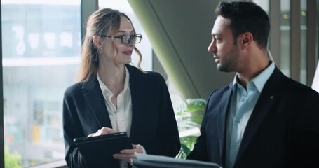 Business coworkers reviewing reports together in office with large windows, discussing and taking notes, medium push in - Powered by Adobe