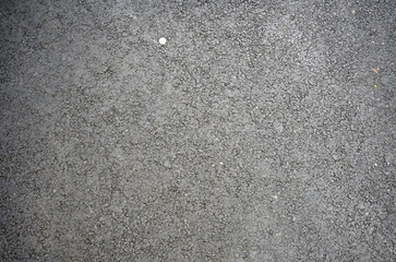 Close-up of gray asphalt surface showing texture and small debris in a casual outdoor setting
