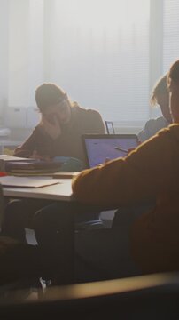 Diverse Group of Students Gathers Around Central Table, Working Together Intensely on Laptops. Collaboration, Group Project Work, Essential Role of Digital Learning in Modern Education. Vertical Shot.