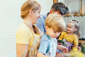 Obraz premium Caucasian family with two preschool children smiling together in home kitchen.
