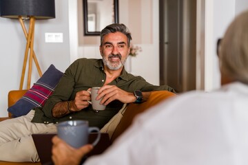 Senior relaxing on sofa chatting with family member at home