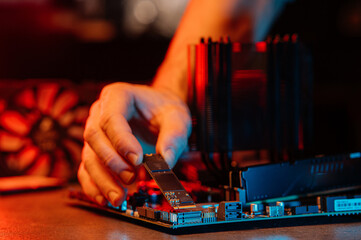 person installs an M.2 NVMe SSD into a modern motherboard connector, demonstrating the assembly of computer equipment in the process.