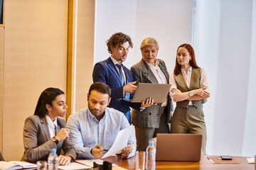Business team collaborating in modern office with laptops and documents during a work meeting