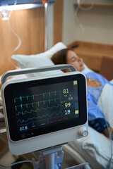 Female patient in hospital with heart rate monitor in foreground