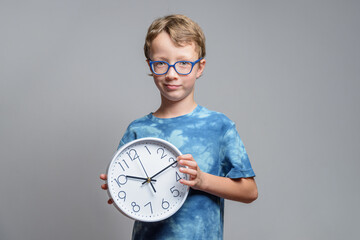 Smiling little boy in glasses holds clock in his hands