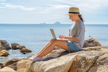 Woman is working on a laptop at a scenic location