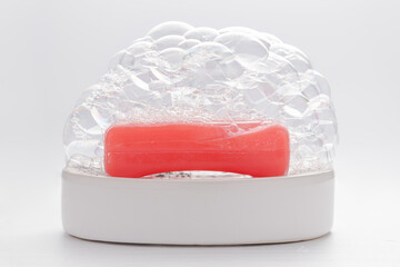 Red soap with soap foam on white background. Cleanness concept