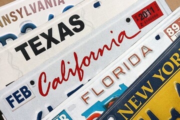 Old US car license plates with various state names close up. Concept of driving in United States. Reaching a car registration