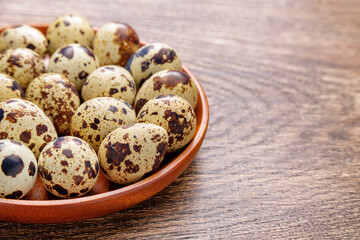 Closeup view of quail eggs in wooden plate on table