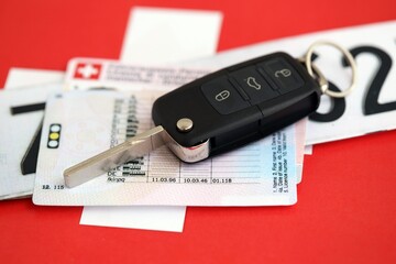 Switzerland car license plate and ignition key on Swiss flag close up. Driving permit and registration concept