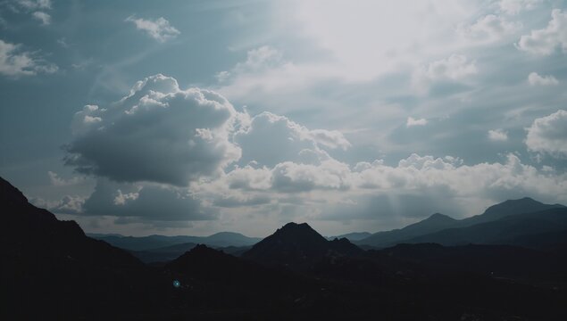 Rocky mountain silhouettes beneath a cloudy daytime sky, erosion risk - Powered by Adobe